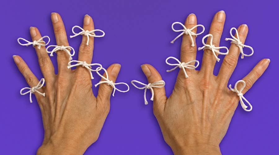 Photo of two hands with ribbons tied on all fingers on purple background