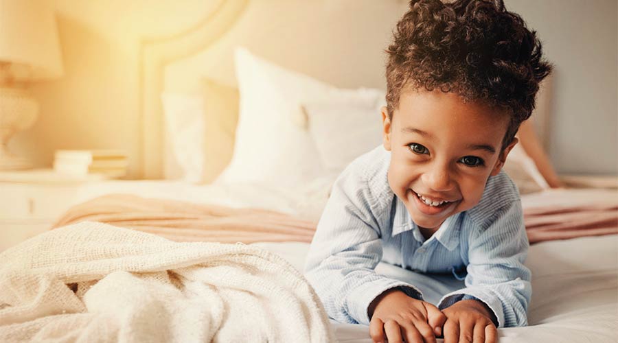 Photo of a smiling little boy on a bed
